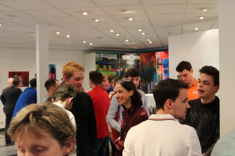 Foto des Get-together bei der Abschlussveranstaltung. Viele Personen stehen in einem Foyer und unterhalten sich.