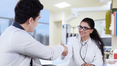 A doctor with a stethoscope handshaking with a patient
