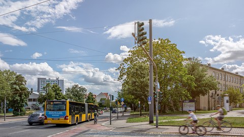 Foto des Verkehrs auf dem TU-Gelände mit Fahrradfahrern, Autos und dem Bus "61".