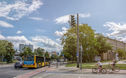 Foto des Verkehrs auf dem TU-Gelände mit Fahrradfahrern, Autos und dem Bus "61".