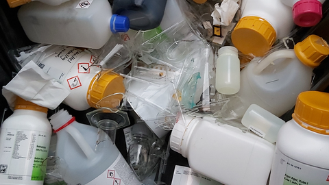 A container is full of plastic lab bottles and broken glass.