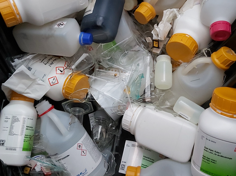 A container is full of plastic lab bottles and broken glass.