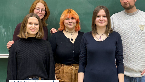 Foto von Studierenden und einem Dozent, die vor einer Tafel stehen auf der mit grüner Kreide das Wort "Sustainability" steht