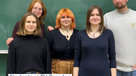 Photo of students and a lecturer standing in front of a blackboard on which the word "Sustainability" is written in green chalk