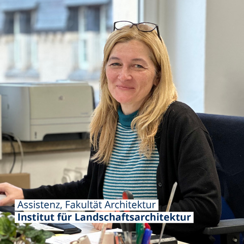 Foto von Ilka Werblow eine blonde Frau, sie sitzt am Schreibtisch und lächelt in die Kamera
