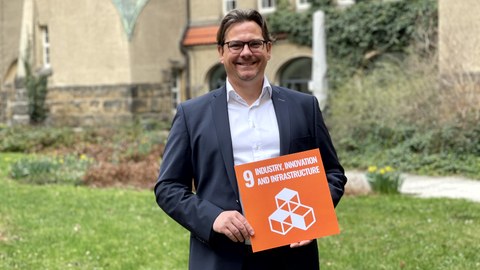 Christian Leßmann mit Tafel von SDG 9