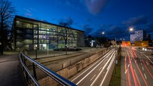 Fotos vom Hörsaalzentrum der TU Dresden am Abend. Im rechten Bildrand sieht man die Straße mit verschwommenen Autolichtern.
