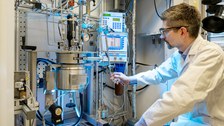 Foto einer Person im Labor, die etwas an einer Anlage prüft und einstellt. 