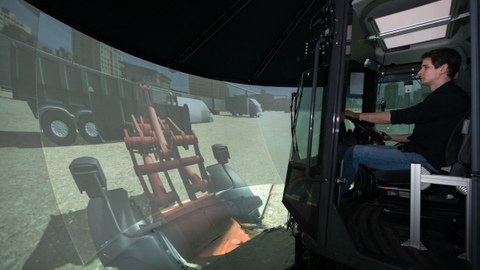 Photo: Man sits in a simulator that simulates the driving behavior of a construction machine and operates it.