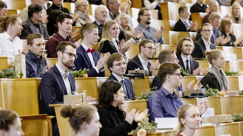 Blick in einen Hörsaal mit festlich gekleideten Studenten.