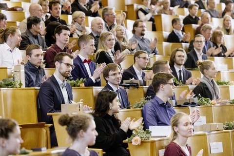 Blick in einen Hörsaal mit festlich gekleideten Studenten.