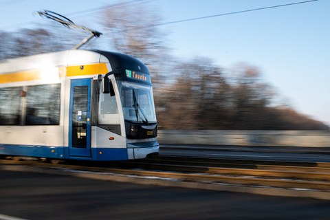 Blick auf ein Straßenbahngleis, von links fährt eine Straßenbahn ins Bild