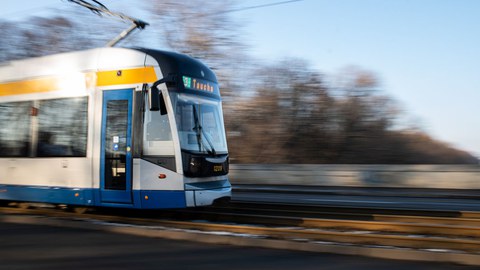 Blick auf ein Straßenbahngleis, von links fährt eine Straßenbahn ins Bild