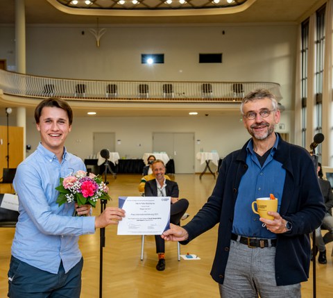 Auf dem Foto ist ein Vertreter der Initiative „Refugee Law Clinic“ mit Prof. Kobel zu sehen.