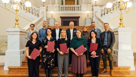 Gruppenbild von festlich gekleideten Personen auf einer Treppe.