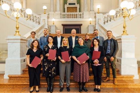 Gruppenbild von festlich gekleideten Personen auf einer Treppe.