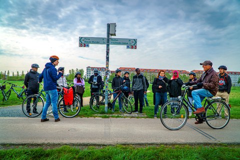 Gruppe von Radfahrern auf einem Radweg an einem Wegweiser.