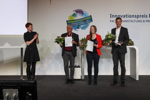 Preisübergabe, 4 Personen stehen auf einer Bühne.