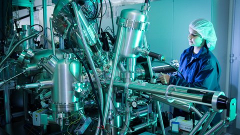 Eine Wissenschaftlerin arbeitet im Reinraum-Labor mit komplexer Technik.