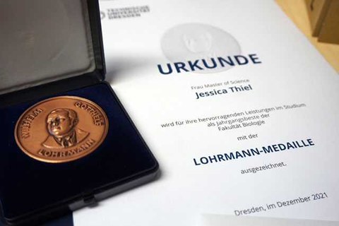 Rechts eine Urkunde zur Verleihung des Lohrmannpreises, links die Lohrmann-Medaille in einer geöffneten, schwarzen Box.