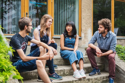 Vier Studenten sitzen auf einer Treppe im Freien.