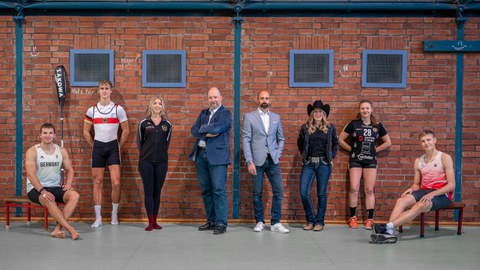 Gruppenbild der Sportstipendiaten mit Prof. Odenbach in einer Sporthalle.