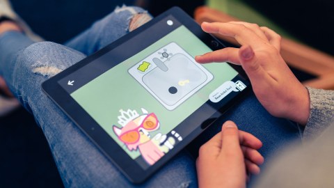 Ein Kind hat ein Tablett mit einem Computerspiel auf den Knien.