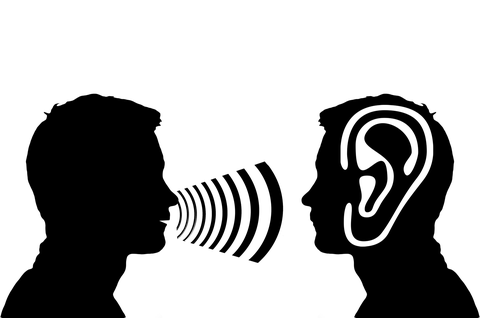 Zwei schwarz gezeichnete Köpfe sehen sich an, der linke spricht, der rechte hört zu, was über ein übergroßes Ohr bezeichnet ist.