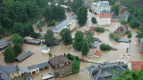 mit schmutzigem Wasser überflutete Straßenkreuzung in Tharandt. Gebäude stehen bis zum ersten Stock im Wasser.