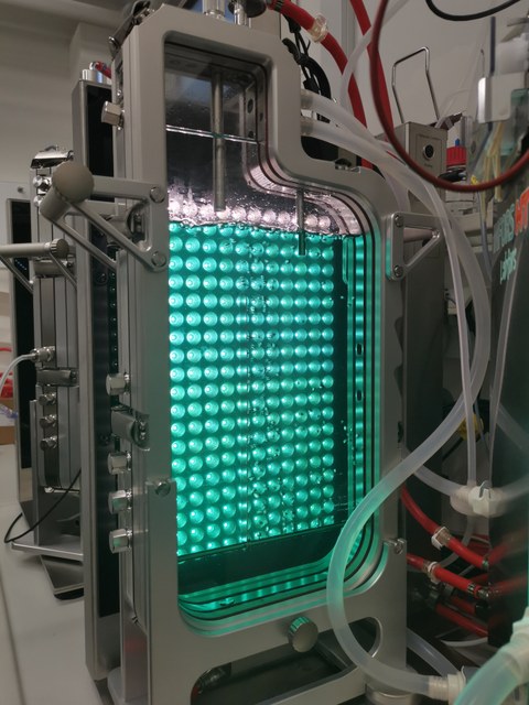 Apparatur aus Metall, darin rechts ein Behälter mit grünen Lampen, der mit einer klaren Flüssigkeit gefüllt ist.