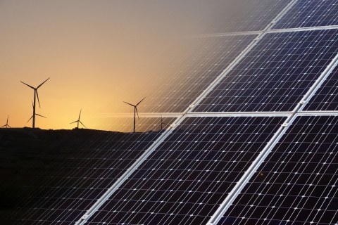 Rechts im Bild Solarpanele, links Windräder vor einem Abendhimmel