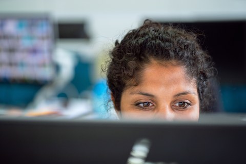 Eine Frau sitzt vor einem Monitor.