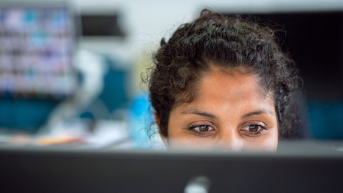 Eine Frau sitzt vor einem Monitor.