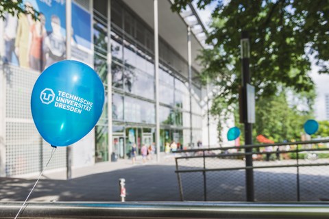 Vorderseite des Hörsaalzentrums mit einem Luftballon mit dem Aufdruck "Technische Universität Dresden" im Vordergrund.