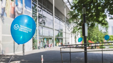 Vorderseite des Hörsaalzentrums mit einem Luftballon mit dem Aufdruck "Technische Universität Dresden" im Vordergrund.
