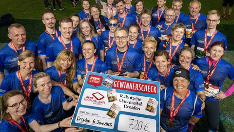 Eine große Gruppe von Läufern präsentieren den Gewinnerscheck der Rewe Teamchallange über 720 Euro.