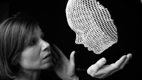 Eine Frau schaut in eine schwebende Maske