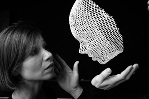 Eine Frau schaut in eine schwebende Maske