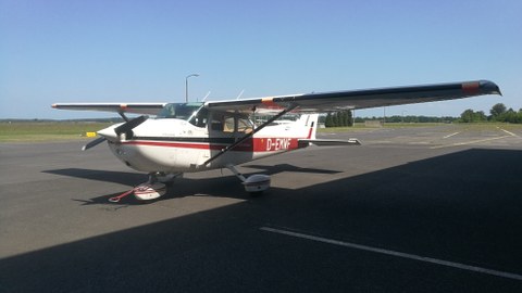 Ein Kleinflugzeug steht auf dem Flugfeld, Blick von der Seite.