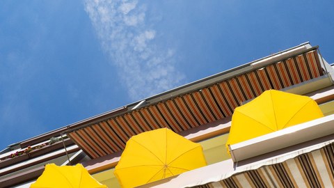 Drei gelbe Sonnenschirme auf einem Balkon.