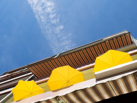 Drei gelbe Sonnenschirme auf einem Balkon.