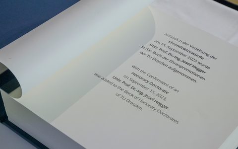 Foto eines aufgeschlagenen Buches. Die aufgeschlagene Seite verkündet, dass Prof. Josef Hegger eine Ehrenpromotionen an der TU Dresden erhalten hat.