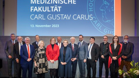 Eine Bühne mit vielen Menschen vor einem Banner "30 Jahre Medizinische Fakultät Carl Gustav Carus"