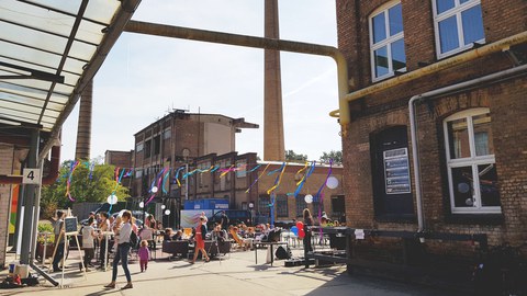 Fest auf einem Werksgelände. Mit bunter Dekoration und vielen Menschen.