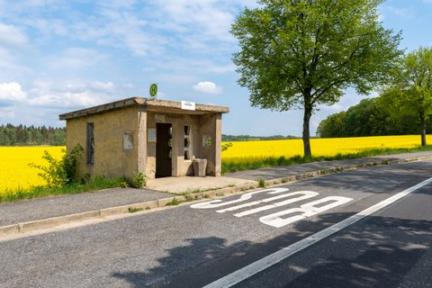 Altes Haltestellenhäuschen vor einem Rapsfeld