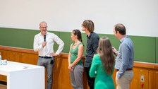 Prof. Hyman mit anderen Personen auf dem Podium mit einem Mikrofon in der Hand
