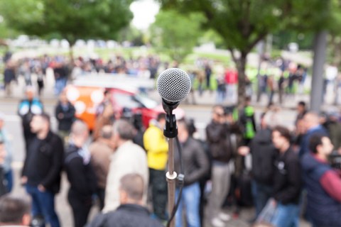 Demonstration: Mikrofon im Fokus vor einer verschwommenen Menschenmenge