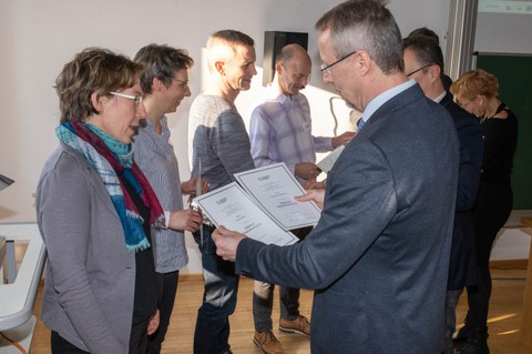 Mehrere Personen bekommen eine Urkunde überreicht.