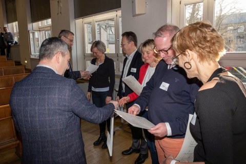 Mehrere Personen bekommen eine Urkunde überreicht.