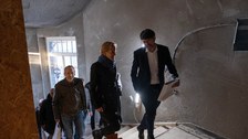 Mehrere Personen gehen auf einer Baustelle in einem GEbäude eine Treppe hinauf.